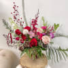 Tall mixed floral arrangement in a glass vase with red, pink, and white blooms