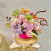 Pink roses and pastel flowers in a bright pink basket with a bow