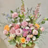 Pastel mixed flower arrangement in a rustic wooden container
