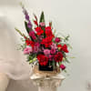 Tall arrangement of red and pink flowers in a black container