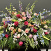 Large mixed floral arrangement with roses, lilies, and blue delphinium