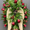 Standing floral spray with red roses and a wooden angel-wing cross