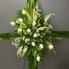 White roses and small white blooms arranged with glossy green leaves on a standing easel.