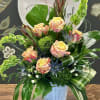 Mixed bouquet of peach roses and green foliage in a blue vase