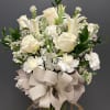 White roses and lilies in a glass vase with a large beige bow