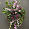 Standing floral spray with pink and purple flowers on a wire easel