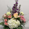 Mixed bouquet of pink, white, and purple flowers in a black vase