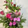 Pink roses and lilies arranged in a clear glass vase