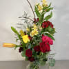 Tall bouquet of red roses, yellow lilies, and red alstroemeria in a glass vase