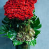 Large red rose arrangement in a tall green vase with succulents