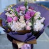 Bouquet of pink and white roses with pale hydrangeas wrapped in purple paper