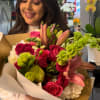 Woman holding a colorful bouquet of roses, lilies, and green blooms