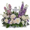 White and purple floral arrangement with a cross centerpiece