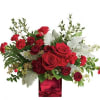 Red roses and carnations in a red glass vase with silver foliage