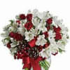 Red roses and white flowers in a glass vase with a red ribbon