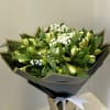 Bouquet of green buds and white filler flowers in a tall vase