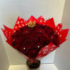 Bouquet of deep red roses wrapped in red patterned paper with a small crown topper
