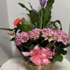 Pink hydrangeas and purple calla lilies in a wicker basket with a pink bow