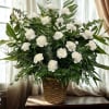 White carnations in a woven basket with mixed greenery