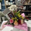 Flower and candy gift arrangement with a teddy bear and heart balloon