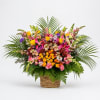 Large mixed flower arrangement in a woven basket with palm fronds