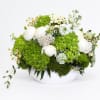 White flowers and green hydrangeas arranged in a white bowl