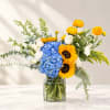 Bouquet of blue hydrangea, sunflowers, and white roses in a glass vase