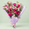 Bouquet of pink and peach roses wrapped in lavender paper