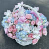 Basket of pink and blue flowers with a white handle