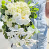 White bouquet with roses and orchids held by a person in a light blue dress