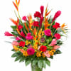 Tropical bouquet with red roses and orange bird-of-paradise in a glass vase