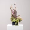 Tall floral arrangement with pink blossoms and curly branches in a black container