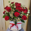Red roses and white filler flowers in a white box with a red ribbon