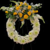 Standing white chrysanthemum wreath with yellow roses and white flowers on a metal easel.