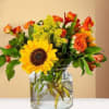 Sunflower and orange rose bouquet in a clear glass vase