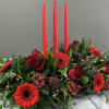 Low floral centerpiece with red roses, red gerbera daisies, and tall red candles