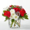 Red roses and white daisies in a clear glass vase with pinecones