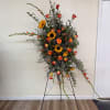 Tall floral spray with sunflowers and orange roses on a stand