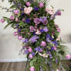 Tall floral spray with pink and purple roses and mixed blooms on a stand