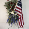 Standing floral spray with red, white, and blue flowers beside an American flag