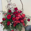 Red roses arranged with a decorative cross and ribbon