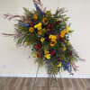 Large standing floral spray with sunflowers, blue flowers, and mixed greenery