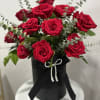 Red roses arranged in a black hatbox with a ribbon