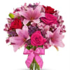 Pink lilies and roses in a glass vase with a pink ribbon