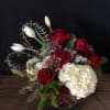 Red roses and white hydrangea in a glass vase with white tulips