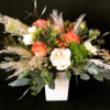 Mixed rose arrangement in a white square vase with airy grasses