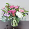 Pink and white mixed bouquet in a glass vase with a green ribbon