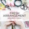 Hands holding pink tulips beside floral arranging tools and supplies