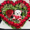 Heart-shaped rose arrangement with a teddy bear and heart decorations