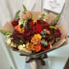 Bouquet of red, orange, and cream flowers wrapped in brown paper